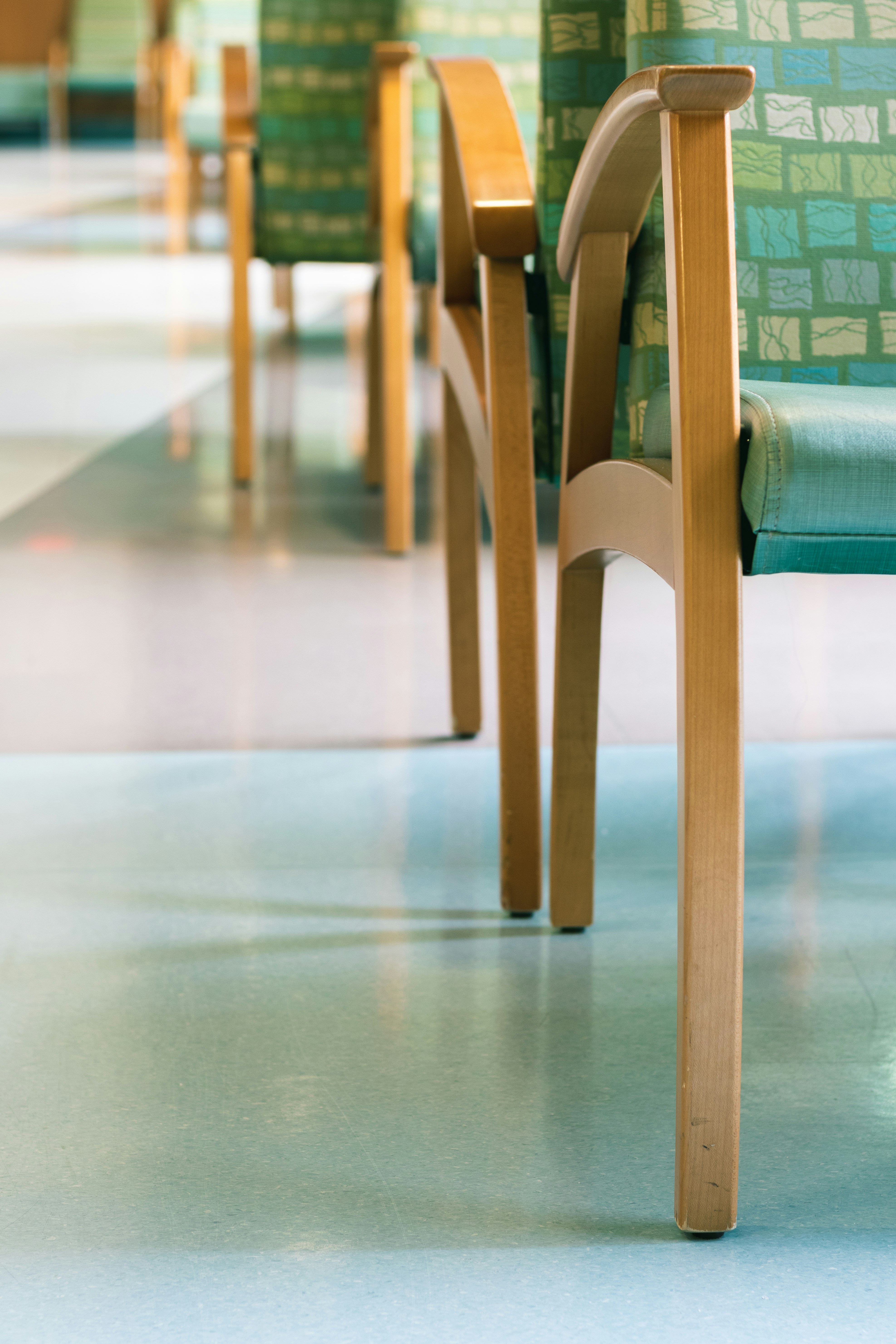 closeup of hospital waiting room chairs with green seats casting shadows on floor